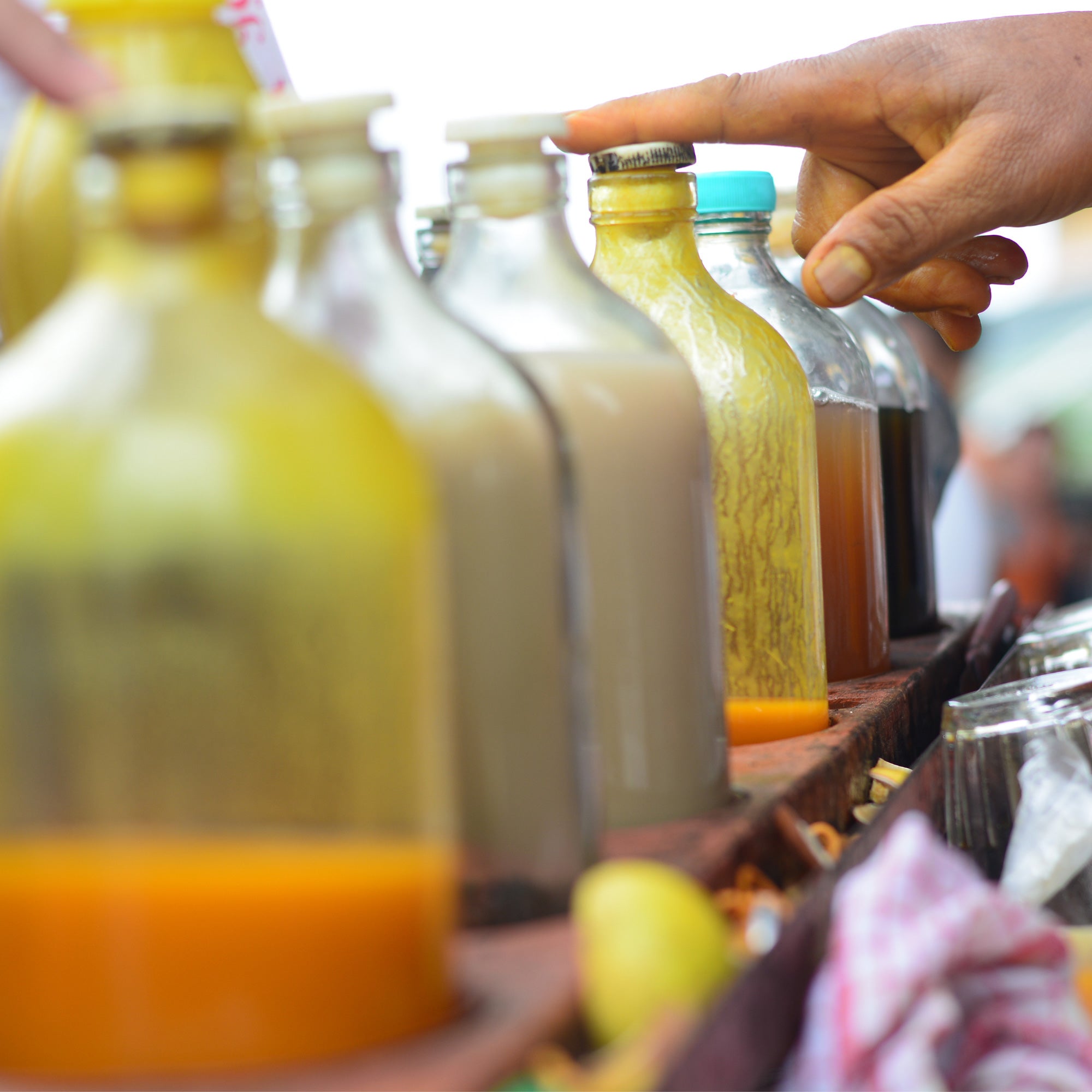 Hand selecting traditional jamu bottles with turmeric and herbal drinks at a market display.